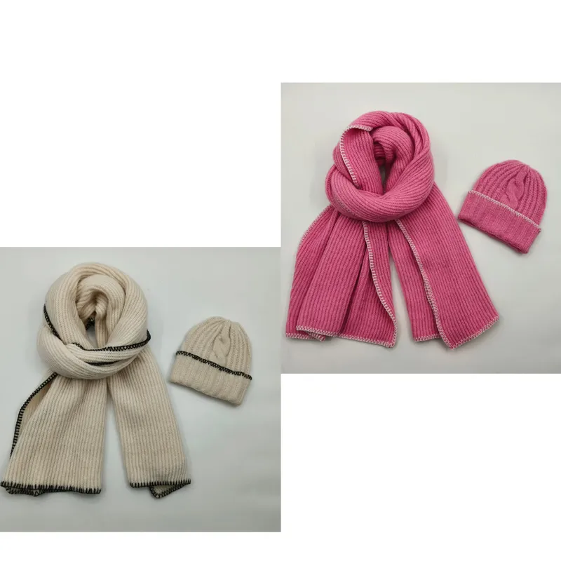 Gerippter Winterschal und passende Zopfmuster-Beanie in Creme mit schwarzen Ziernähten sowie in Rosa mit weißen Kontrastnähten, flach fotografiert
