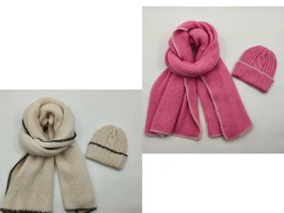 Gerippter Winterschal und passende Zopfmuster-Beanie in Creme mit schwarzen Ziernähten sowie in Rosa mit weißen Kontrastnähten, flach fotografiert