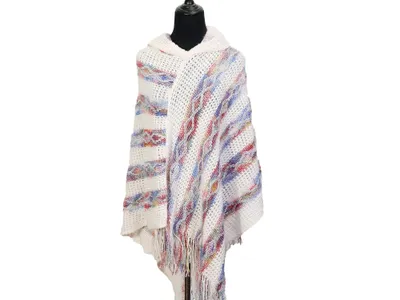Elfenbeinfarbener Strickponcho mit Kapuze, buntem Streifenmuster in Rot und Blau sowie Fransenabschluss am Saum, auf schwarzer Schneiderpuppe präsentiert