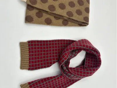 Zwei Strickschals nebeneinander: sandbeige mit braunen Punkten und cremefarbenen Rippenden, rot-grau mit Gittermuster und khakifarbenen Abschlüssen, Draufsicht