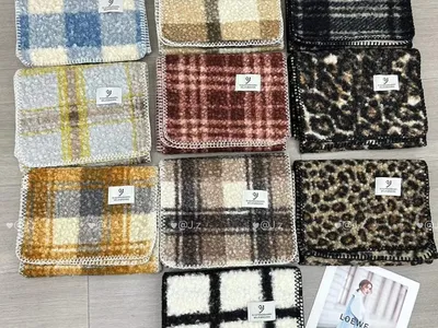 Zehn doppelseitige Bouclé-Waschlappen mit lockiger Wolltextur in Karo-, Leoparden- und Schachbrettmuster, flach auf dem Boden ausgebreitet