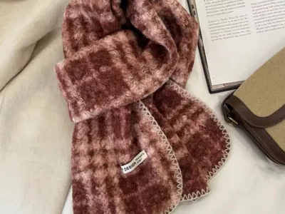 Weicher Mohair-Schal mit Karomuster in Rosé und Burgund, mit cremefarbener Sticknaht am Rand, zusammen mit Buch und Handtasche in Szene gesetzt