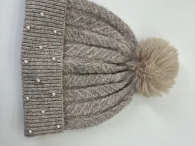 Graue Zopfstrickmütze mit fluffigem Kunstfell-Pompon oben und Perlen-Akzenten am gerippten Umschlagbund