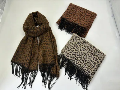 Drei Schals mit Leopardenprint und schwarzen Fransen in den Farbtönen Dunkelbraun, Caramelbraun und Cremeweiß, flach ausgelegt