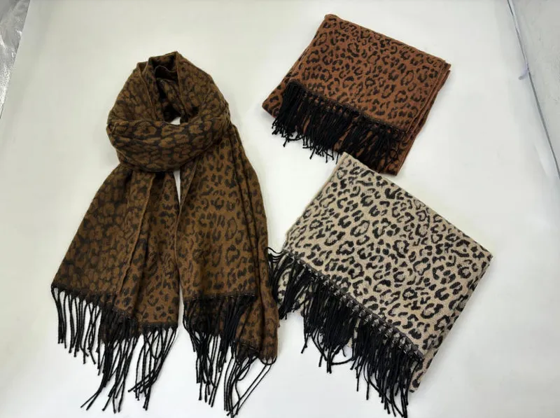 Drei Schals mit Leopardenprint und schwarzen Fransen in den Farbtönen Dunkelbraun, Caramelbraun und Cremeweiß, flach ausgelegt