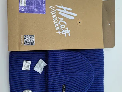 Royalblaue Rippenstrick-Wintermütze und passender Schal mit Logoaufnäher, präsentiert mit Kraftpapier-Geschenkbox