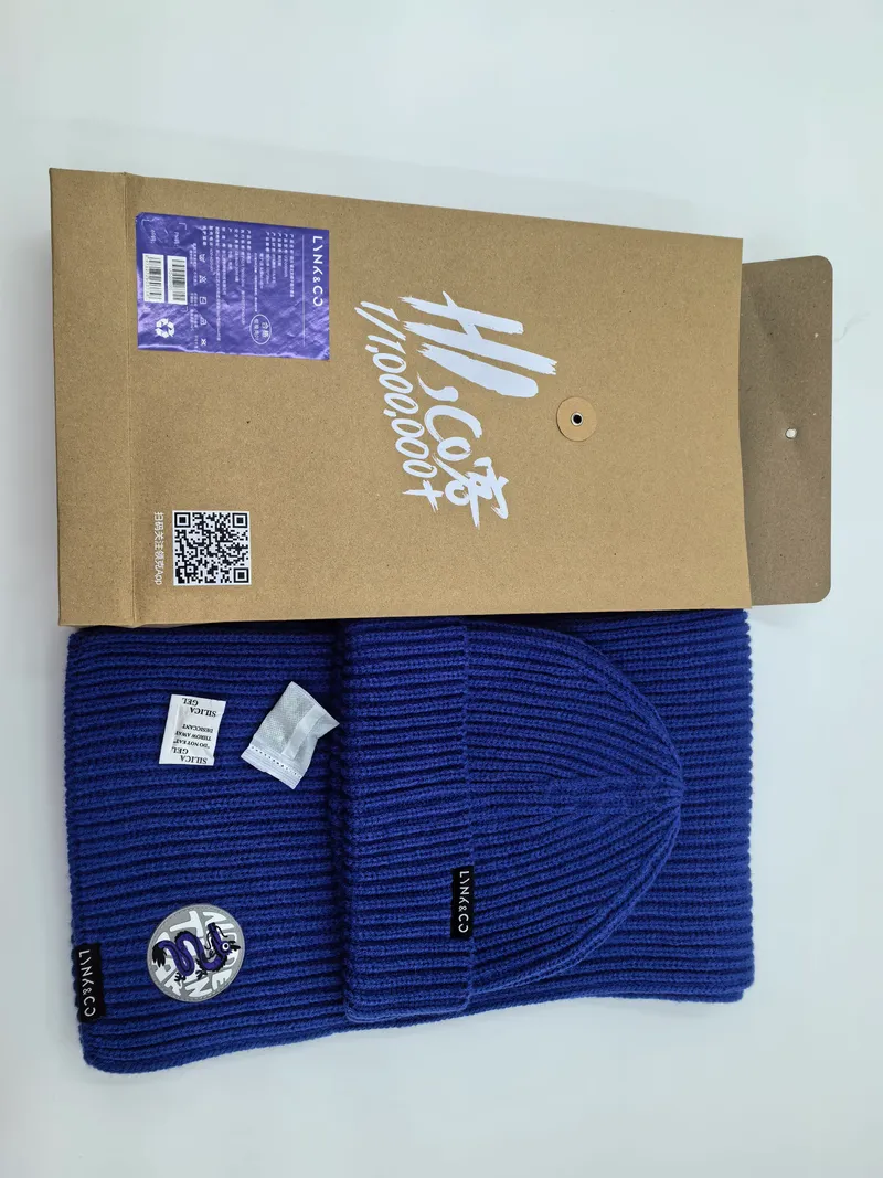 Royalblaue Rippenstrick-Wintermütze und passender Schal mit Logoaufnäher, präsentiert mit Kraftpapier-Geschenkbox