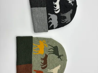 Zwei Jacquard-Strickmützen nebeneinander mit Wildtier-Silhouetten wie Elch, Wolf, Bär und Hirsch in den Farben Anthrazit und Salbeigrün