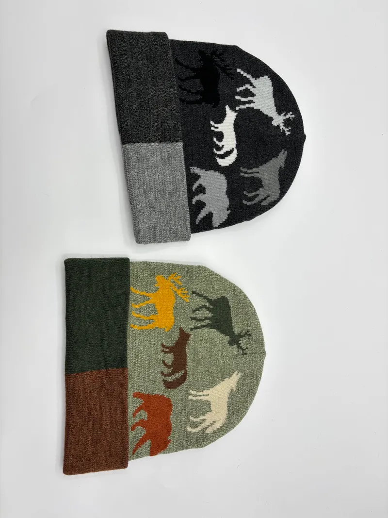 Zwei Jacquard-Strickmützen nebeneinander mit Wildtier-Silhouetten wie Elch, Wolf, Bär und Hirsch in den Farben Anthrazit und Salbeigrün