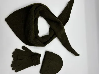 Olivgrünes Winteraccessoire-Set mit dreieckigem Stricktuch, anliegenden Handschuhen und Rippenstrickmütze auf weißem Hintergrund