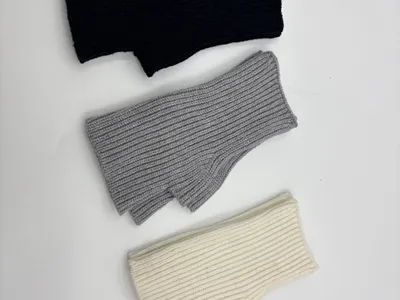 Fingerfreie Rippenstrickhandschuhe in drei Farben – Schwarz, Mittelgrau und Cremeweiß – als Flachfoto auf hellem Untergrund