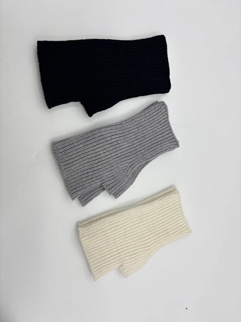 Fingerfreie Rippenstrickhandschuhe in drei Farben – Schwarz, Mittelgrau und Cremeweiß – als Flachfoto auf hellem Untergrund