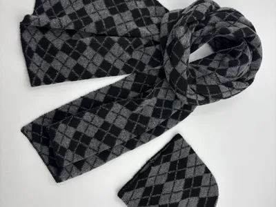 Strickmütze und passender Schal mit klassischem Argyle-Rautenmuster in Grau und Schwarz, flach auf weißem Hintergrund