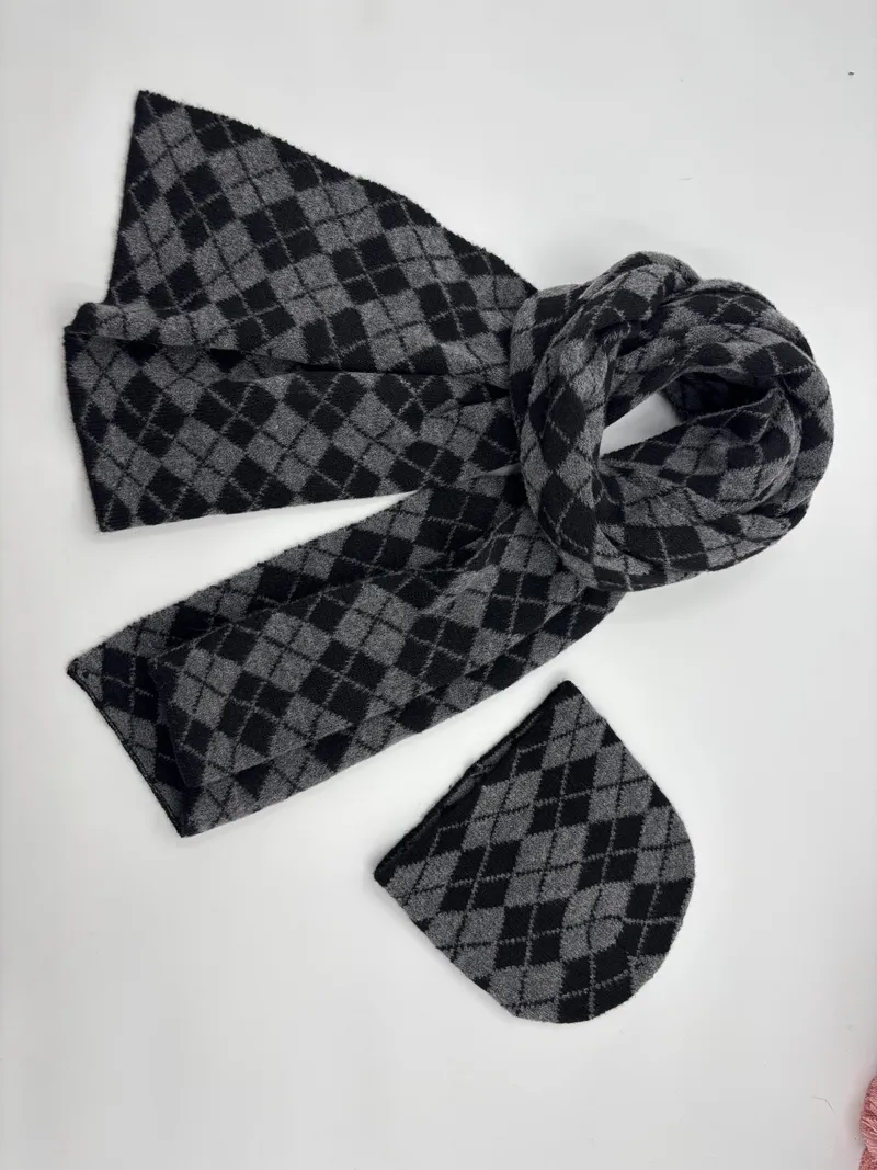 Strickmütze und passender Schal mit klassischem Argyle-Rautenmuster in Grau und Schwarz, flach auf weißem Hintergrund