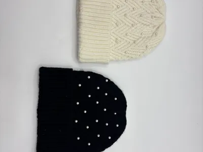 Zwei Rippenstrickmützen nebeneinander – eine in Creme mit Chevronmuster und eine in einfarbigem Schwarz, beide mit Perlenmotiven und Umschlagbündchen