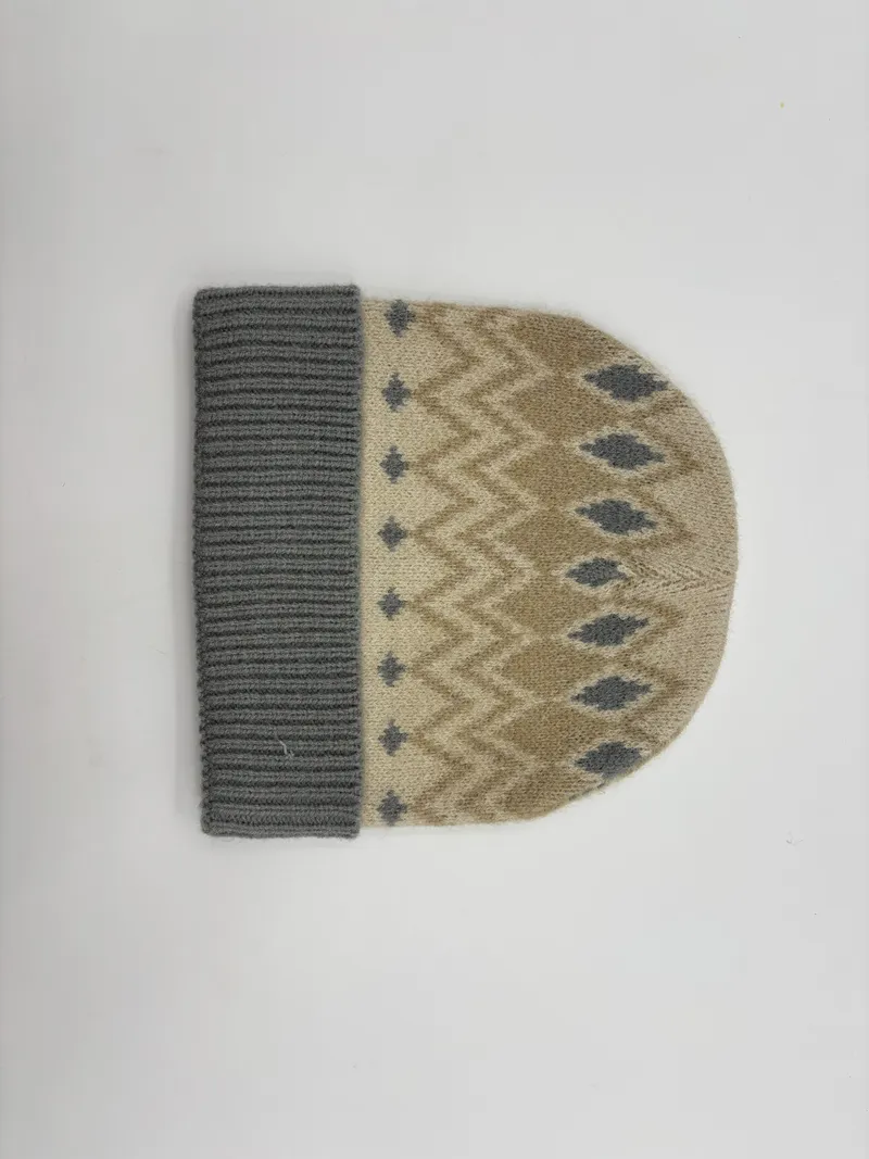 Beigefarbene Strickmütze mit grauem Fair-Isle-Rauten- und Zickzackmuster sowie grauem Rippenbündchen, Flachlage auf weißem Hintergrund