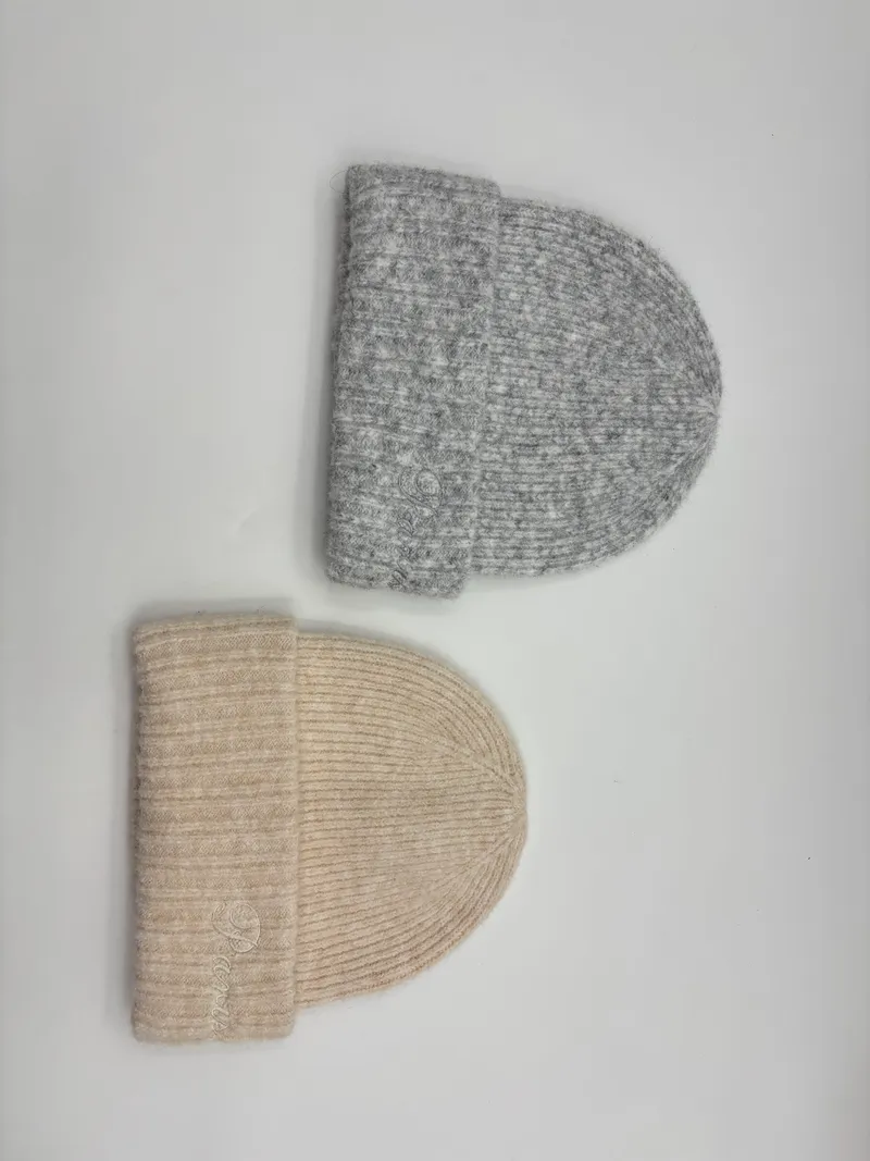 Zwei Rippenstrickmützen mit Umschlagbündchen aus Wollmischung – eine in Heathergrau, eine in Cremeweiß, auf weißem Hintergrund