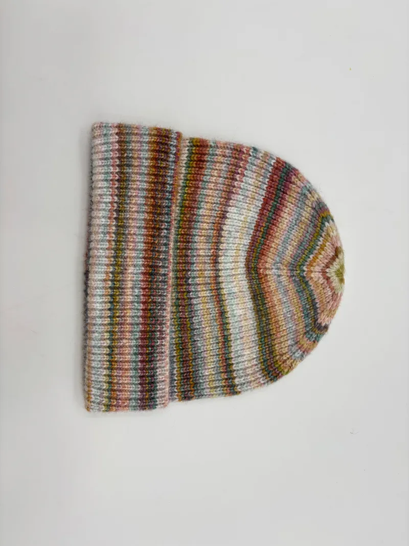 Gestrickte Wintermütze mit mehrfarbigen Space-Dye-Streifen in Rosa, Grün, Blau und Braun, gefaltetem Bündchen, auf weißem Hintergrund