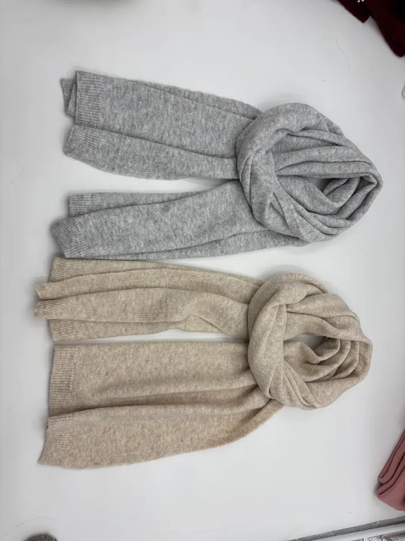 Zwei weiche Strickschals flach übereinandergelegt – einer in Hellgrau, einer in Beige, mit gerippten Enden und kuscheligen Strickdetails