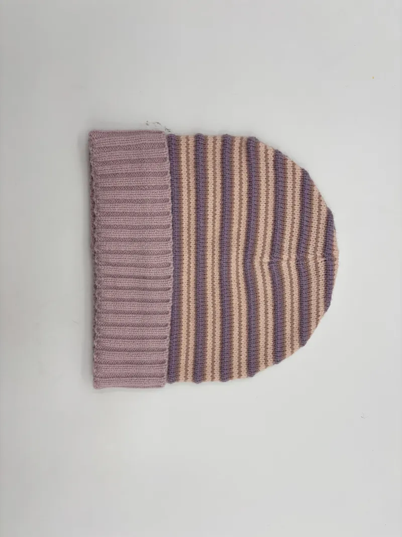 Strickmütze mit lila und beigen Querstreifen sowie einfarbigem lavendelfarbenem Umschlagbündchen, Flachlage auf weißem Hintergrund