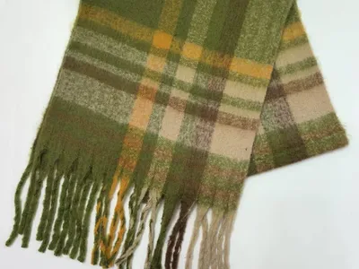Gefalteter Wollmix-Schal in Grün, Gold und Beige mit gedrehten Fransenbommel auf weißem Untergrund