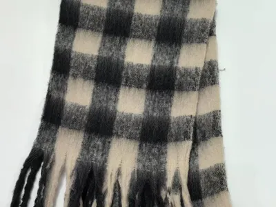 Großkarierter Winterschal in Schwarz-Weiß im Buffalo-Check-Design mit Fransenenden, gefaltet auf weißem Hintergrund