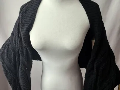 Schwarzer grob gestrickter Bolero-Shrug mit breiten Fledermausärmeln auf einer Schneiderpuppe
