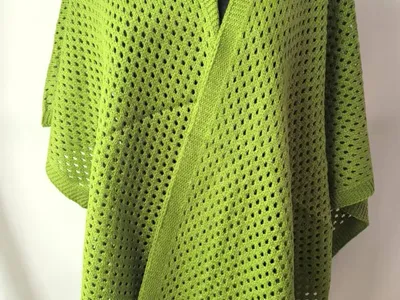 Limettengrüner Netzstrick-Wickelponcho mit V-Ausschnitt und Rippbündchen auf schwarzer Schneiderpuppe