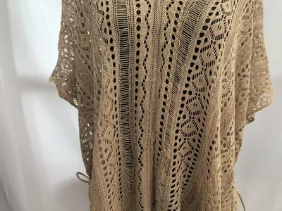Beiger Häkelponcho mit floralem Spitzenmuster, V-Ausschnitt, kurzen Ärmeln und Quastenfransen-Saum auf Schneiderpuppe