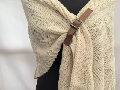 Dicker cremefarbener Zopfstrickschal mit braunem Leder-Schnallenverschluss auf schwarzer Schneiderpuppe – gemütliches Winteraccessoire
