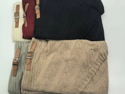 Fünf gefaltete Kuscheldecken aus Grobstrick in Beige, Grau, Schwarz, Burgund und Creme mit braunen Leder-Schnallenriemen