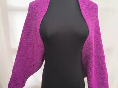 Pinker Grobstrick-Bolero Shrug in Magenta mit Ballonärmeln und offenem Vorderausschnitt auf schwarzer Kleiderpuppe