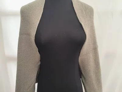 Taupefarbener Kurzstrick-Shrug mit langen Ärmeln auf schwarzer Kleiderpuppe