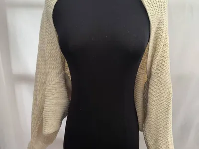 Cremefarbener Kurzstrick-Bolero Shrug mit langen Ärmeln und Rippbündchen auf schwarzer Kleiderpuppe