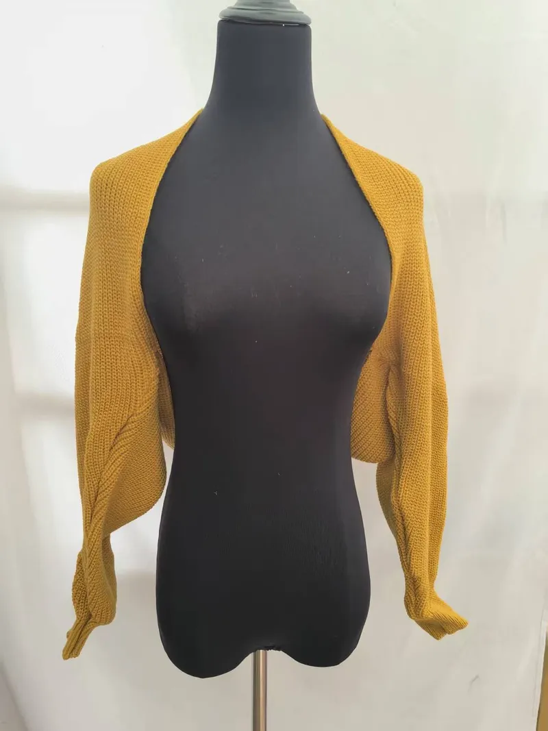 Senfgelber Grobstrick-Bolero Shrug mit langen Ärmeln auf schwarzer Kleiderpuppe