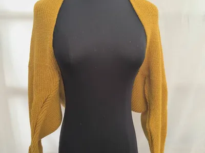 Senfgelber Grobstrick-Bolero Shrug mit langen Ärmeln auf schwarzer Kleiderpuppe
