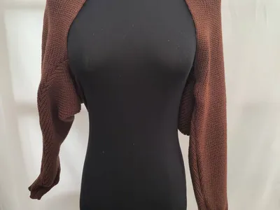 Brauner Kurzstrick-Bolero Shrug mit langen Ärmeln auf schwarzer Schneiderpuppe vor weißem Hintergrund