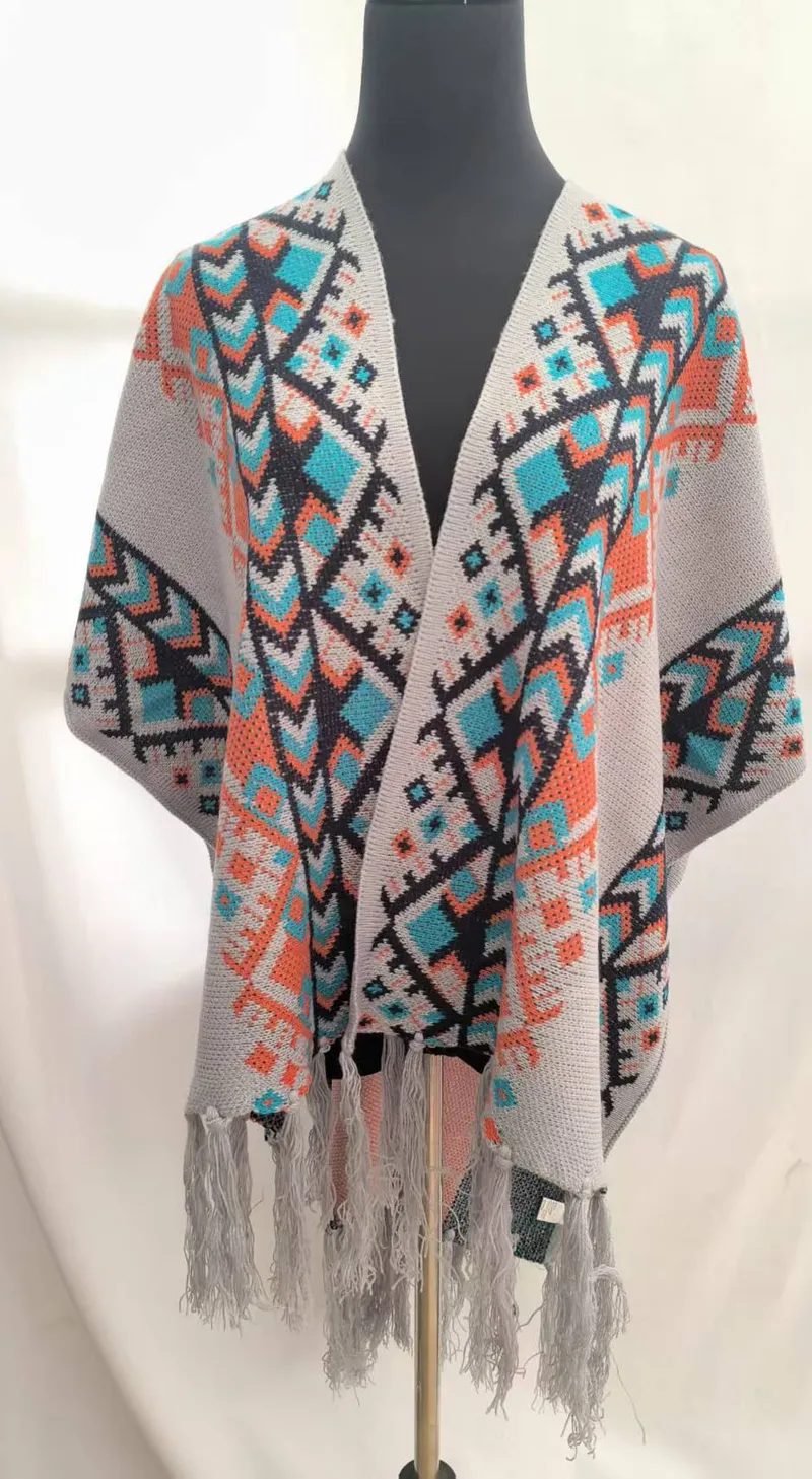 Offener Strickmantel im Boho-Stil mit geometrischem Muster in Grautönen, Petrol und Orange, mit Fransenabschluss an Saum und Ärmeln