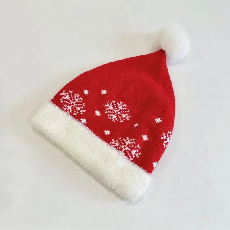 Klassische Nikolausmütze aus Strickstoff in Rot mit weißem Schneeflockenallover, plüschigem Krempenabschluss und fluffigem Pompom
