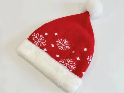 Klassische Nikolausmütze aus Strickstoff in Rot mit weißem Schneeflockenallover, plüschigem Krempenabschluss und fluffigem Pompom
