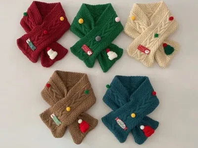Fünf bunte Kinderschals in Rot, Grün, Creme, Braun und Petrol mit weihnachtlichen Dekorationen und Bommeln aus weichem Strickgarn