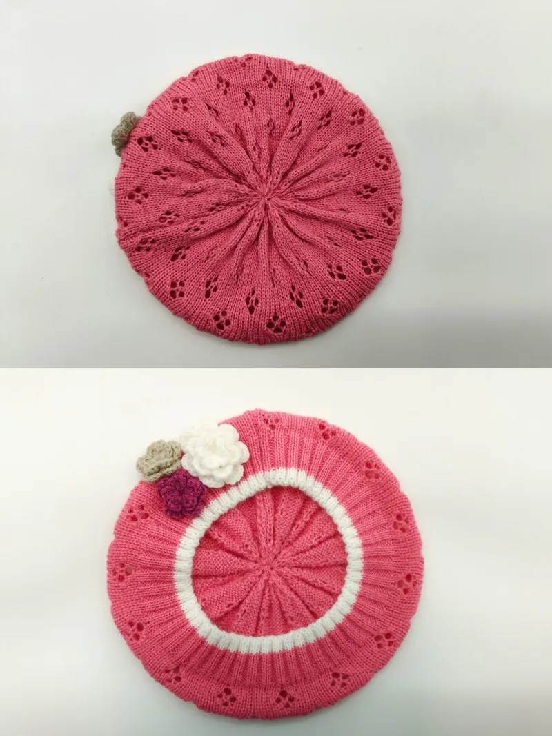 Rosa gestrickte Baskenmütze mit Lochstrickmuster, weißem Rippenbündchen und drei Häkelblumen-Applikationen in Rosa, Weiß und Beige