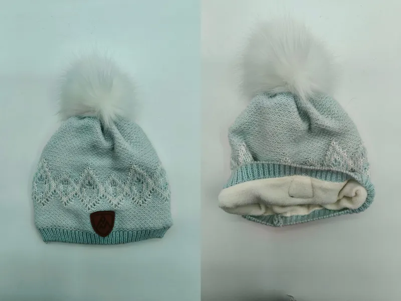 Mintgrüne Strickmütze mit weißem Kunstfell-Bommel, Jacquardmuster, Fleecefutter und Leder-Logoaufnäher
