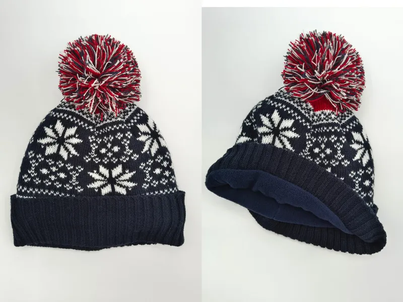 Navyblaue Strickmütze mit weißem Fair-Isle-Schneeflockendesign, rotem und weißem Mehrfarb-Bommel und Fleece-Innenfutter in Vorder- und Seitenansicht