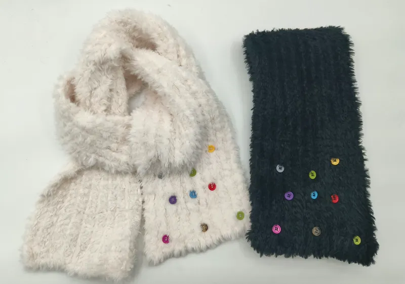 Zwei wuschelige Strickschals mit bunten Knöpfen in verschiedenen Farben, einer in Cremeweiß und einer in Marineblau, Flachaufnahme auf weißem Hintergrund