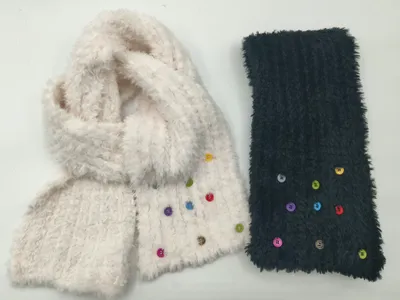 Zwei wuschelige Strickschals mit bunten Knöpfen in verschiedenen Farben, einer in Cremeweiß und einer in Marineblau, Flachaufnahme auf weißem Hintergrund