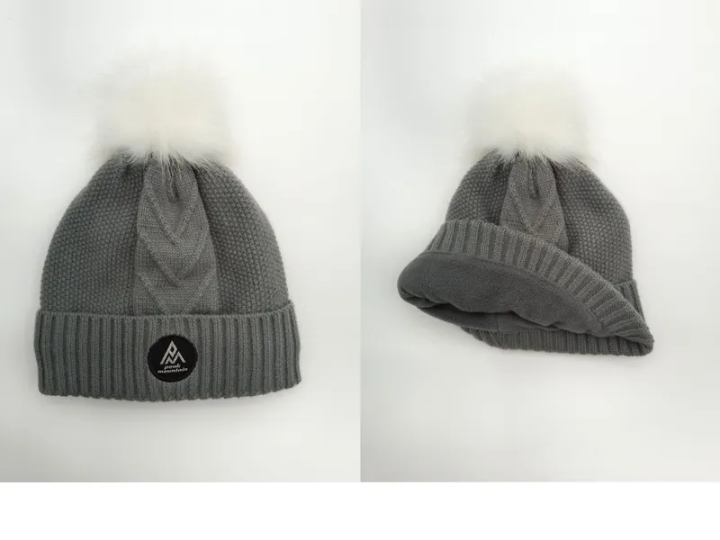 Warme Wintermütze in Grau mit grobem Zopfstrickmuster, flauschigem Fellbommel und sichtbarem Fleece-Innenfutter
