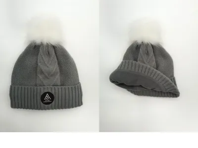 Warme Wintermütze in Grau mit grobem Zopfstrickmuster, flauschigem Fellbommel und sichtbarem Fleece-Innenfutter