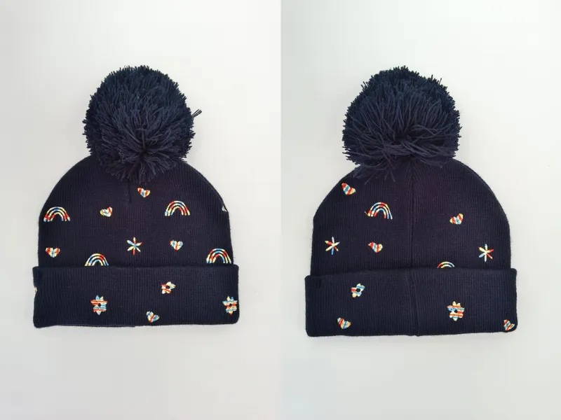 Marine-blaue Strickmütze mit großem Bommel, farbenfrohen gestickten Regenbögen, Herzen, Sternen und Blümchen von vorne und seitlich