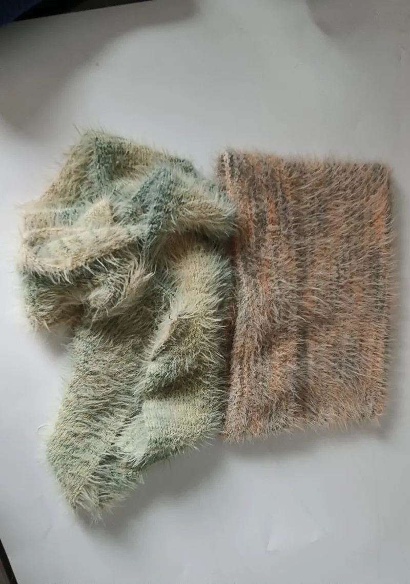 Zwei Eyelash-Garn-Strickproben in Salbeigrün und Altrosa auf weißem Untergrund
